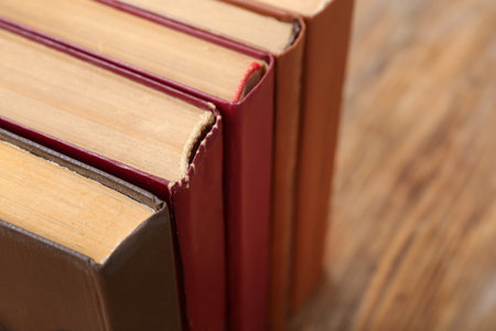 Old hardcover books on wooden background, closeup