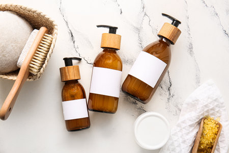 Bottles of shampoo, sea salt and brush on white marble backgroundの写真素材