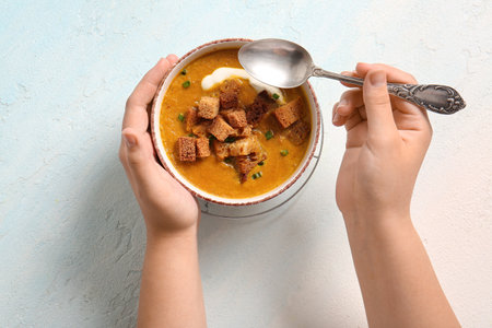 Woman eating tasty cream soup with croutons on white backgroundの写真素材