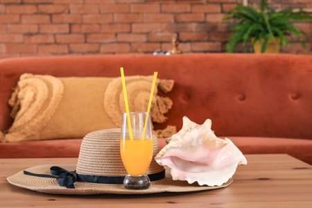 Summer hat, orange juice and seashell on wooden table in living room, closeupの写真素材