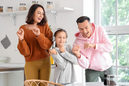 Happy family dancing together in kitchen at homeの写真素材