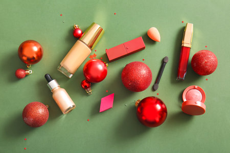 Composition with makeup products and red Christmas balls on dark green backgroundの写真素材