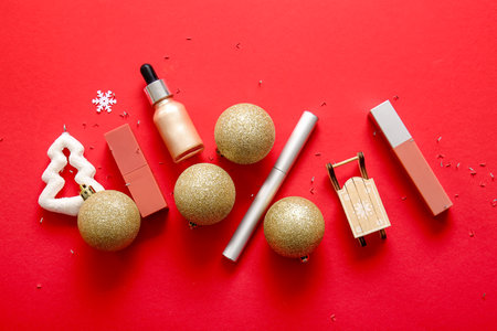 Composition with decorative cosmetics and Christmas decor on red backgroundの写真素材