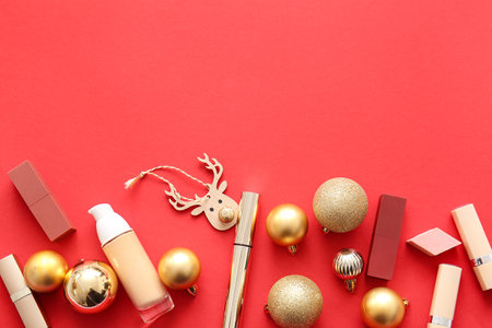 Composition with makeup products and golden Christmas balls on red backgroundの写真素材