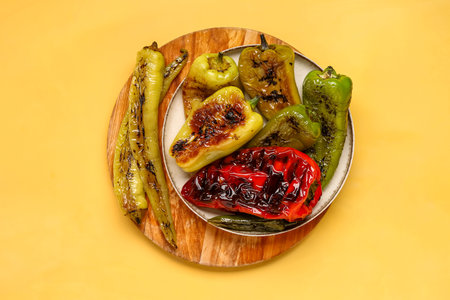 Plate with different grilled peppers on yellow backgroundの写真素材