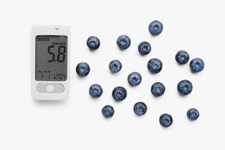 Glucometer with blueberries on white background. Diabetes concept