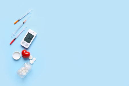 Glucometer with syringes, heart and pills on blue background. Diabetes conceptの写真素材