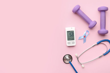 Glucometer, blue ribbon, stethoscope and dumbbells on pink background. Diabetes conceptの写真素材