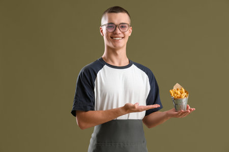 Young man with French fries on color background
