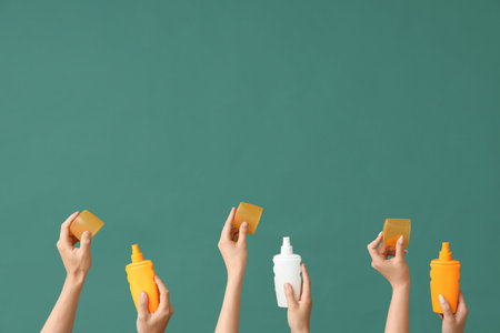 Female hands with bottles of sunscreen cream on green backgroundの写真素材