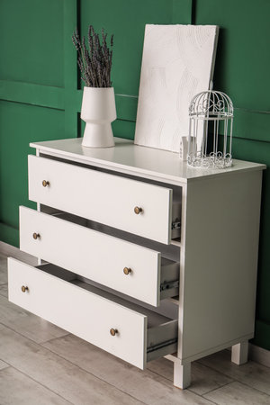 Vase with lavender and painting on white chest of drawers near green wallの写真素材