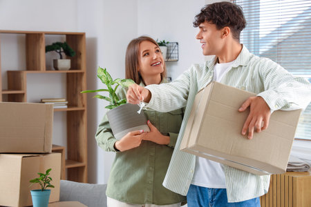 Young couple with keys and moving box in their new flat