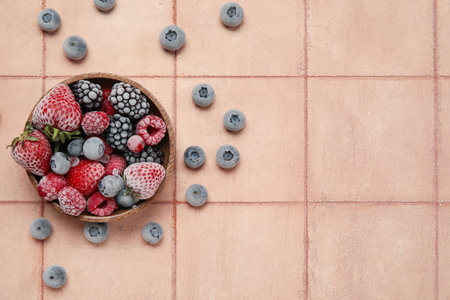 Bowl of different frozen berries on color tile backgroundの写真素材
