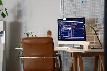 Programmer's workplace with computer monitor and glowing lamp in office