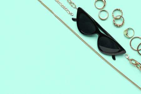Stylish sunglasses with beautiful jewelery on turquoise backgroundの写真素材
