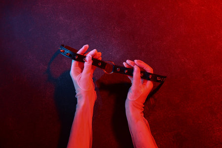 Woman with strap from sex shop on dark color backgroundの写真素材
