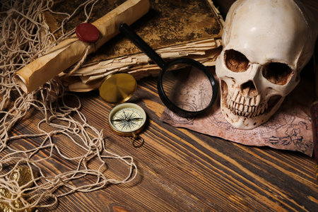 Human skull with old manuscripts, world map and travel equipment on brown wooden backgroundの写真素材