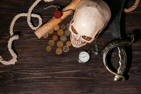Human skull with sword, pocket watch, scroll and coins on brown wooden backgroundの写真素材