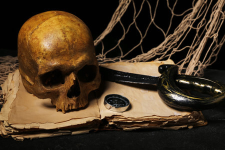 Human skull with sword, old manuscripts, net and compass on black backgroundの写真素材