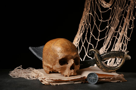 Human skull with sword, old manuscripts, net and compass on black backgroundの写真素材