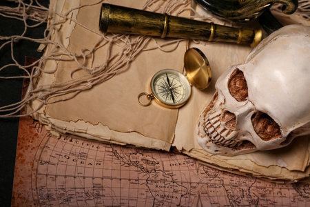 Human skull with spyglass, old manuscripts, world map and compass on black backgroundの写真素材