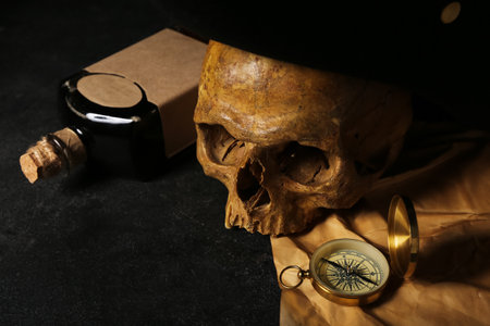 Human skull with compass, bottle of rum and pirate hat on black backgroundの写真素材
