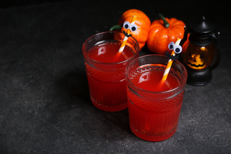 Glasses of delicious red cocktail for Halloween and pumpkins on dark background, closeupの写真素材