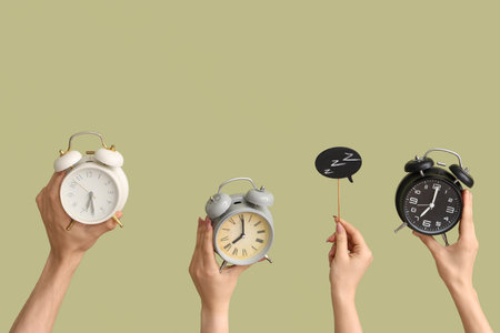 Hands holding different alarm clocks and speech bubble on green backgroundの写真素材