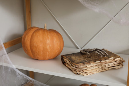 Halloween pumpkin with book on shelf near light wallの写真素材