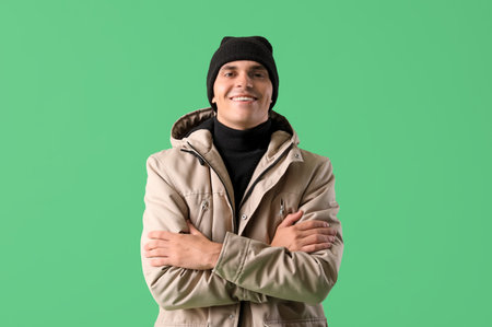 Young man in winter clothes on green backgroundの写真素材