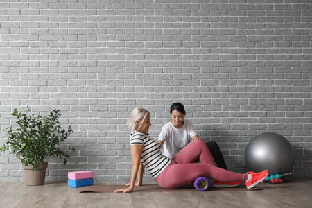 Mature woman training on mat with therapist in rehabilitation center
