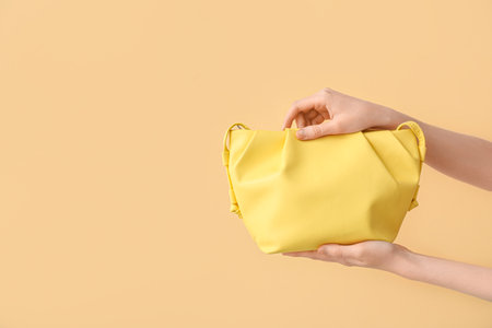 Female hands with stylish yellow bag on color backgroundの写真素材