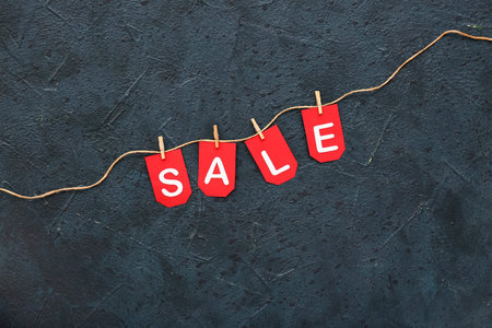 Rope, clothespins and flags with the word SALE on black background
