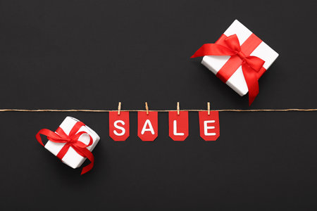 Gift boxes, rope, clothespins and flags with the word SALE on black backgroundの写真素材