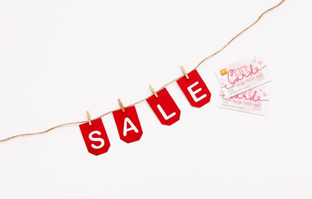 Credit cards, rope, clothespins and flags with the word SALE on white backgroundの写真素材