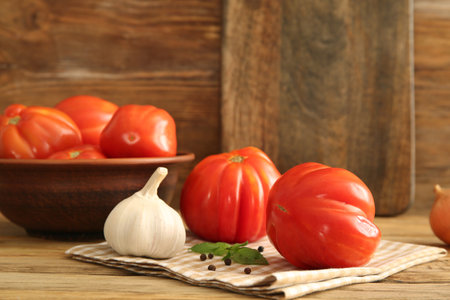 Bowl with fresh ripe tomatoes and different spices on wooden backgroundの写真素材