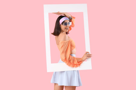 Beautiful young woman with frame on pink backgroundの写真素材