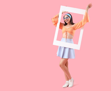 Beautiful young woman with frame on pink backgroundの写真素材