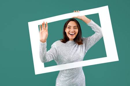 Beautiful young woman with frame on green background