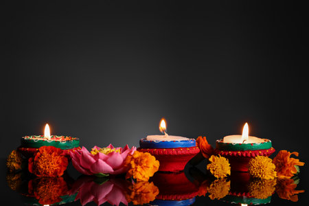 Burning candles with beautiful flowers for celebration of Diwaly on dark backgroundの写真素材