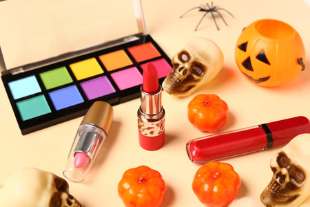 Lipsticks and different decorative cosmetics with Halloween decor on beige backgroundの写真素材