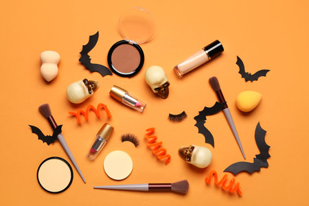 Lipsticks and different decorative cosmetics with Halloween decor on orange backgroundの写真素材
