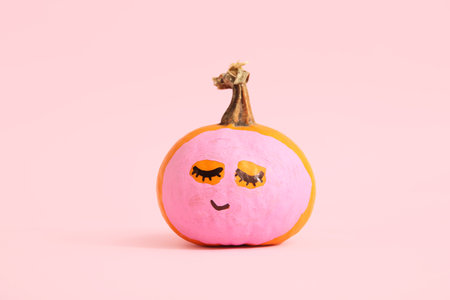 Pumpkin with drawn face and mask on pink backgroundの写真素材