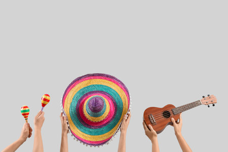 Female hands holding maracas, ukulele and sombrero on gray backgroundの写真素材