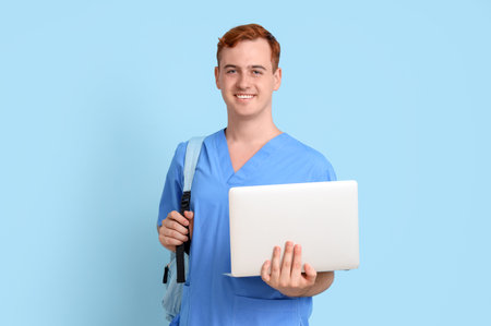 Male medical student with laptop on blue backgroundの写真素材