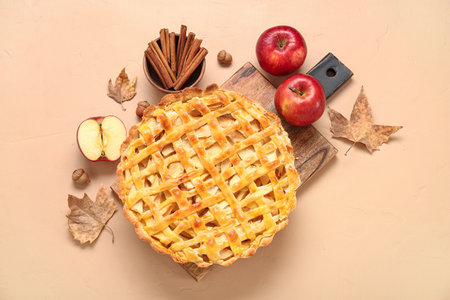 Wooden board with delicious apple pie and ingredients on orange backgroundの写真素材