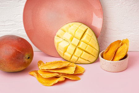 Slices of dried mango and fresh fruit on pink tableの写真素材
