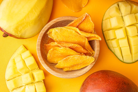 Wooden bowl with slices of dried mango on orange backgroundの写真素材