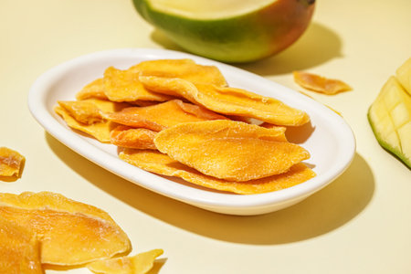 Plate with slices of dried mango on yellow backgroundの写真素材