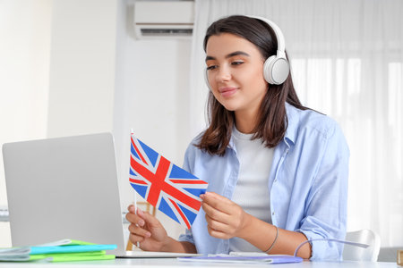 Young woman in headphones with UK flag learning English language online at homeの写真素材